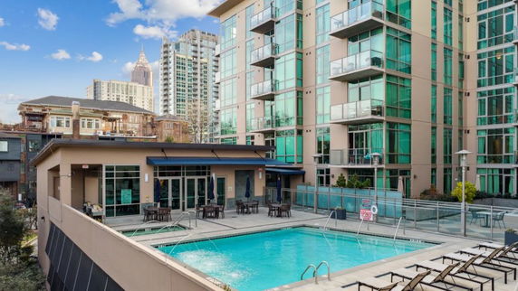 Outdoor swimming pool in front of a modern multi-story apartment building.