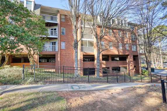 Front view of a multi-story brick apartment building with balconies.