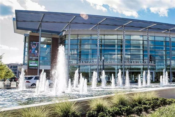 Front view of a modern building with large glass windows and a fountain in the foreground.