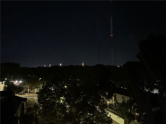 Nighttime panoramic view of surrounding areas with city lights in the distance.