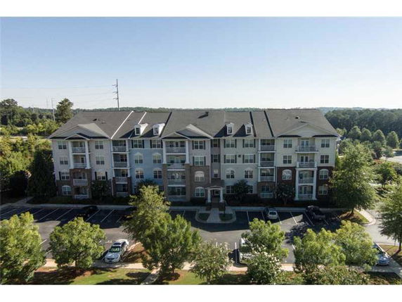 Front view of a multi-story apartment building with balconies and parking area.