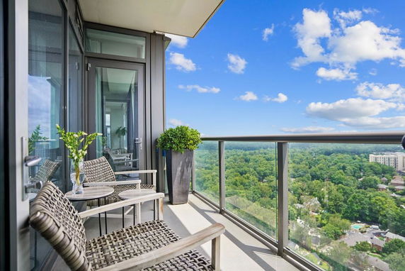 Balcony with chairs and a table overlooking a vast green landscape