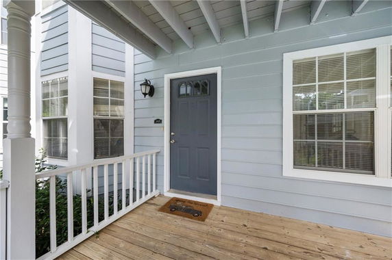 Front view of a house with a blue door and a wooden porch.