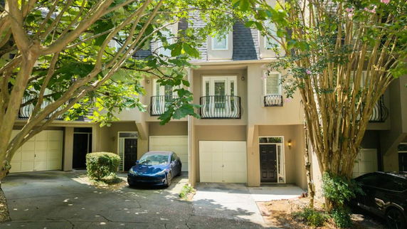Front view of a multi-story townhouse with garages and balconies.