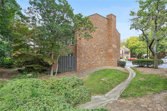 Side view of a brick building with a chimney and surrounding trees.