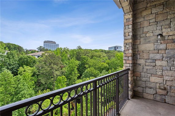Panoramic view from a building showing nearby trees and a distant view of several buildings.