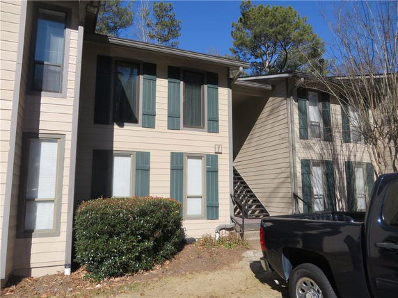 Front view of a two-story residential building with multiple large windows and siding.