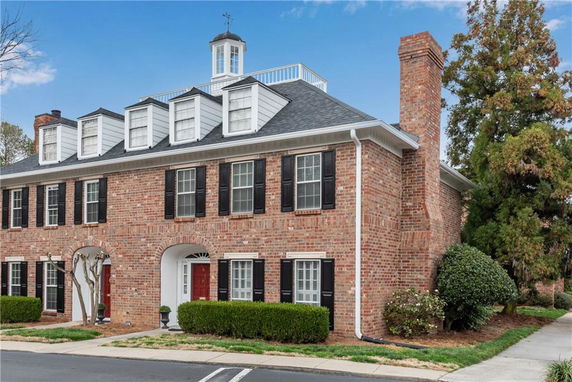 Front view of a brick building with multiple windows and a chimney.