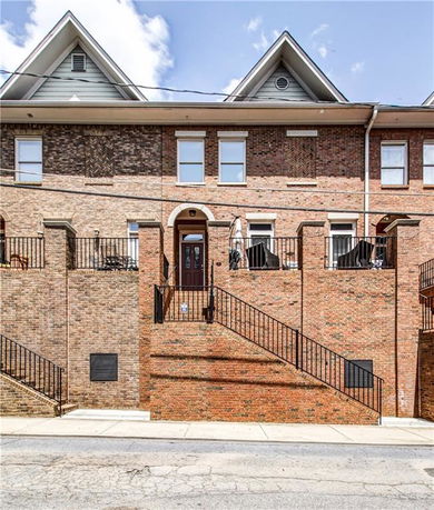 Front view of a multi-story brick building with staircase leading to the entrance.
