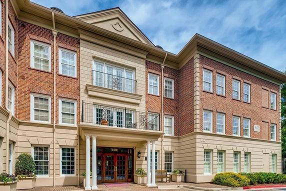 Front view of a three-story brick building with decorative columns and balconies.