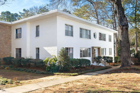 Front view of a two-story house with white brick exterior and multiple windows.