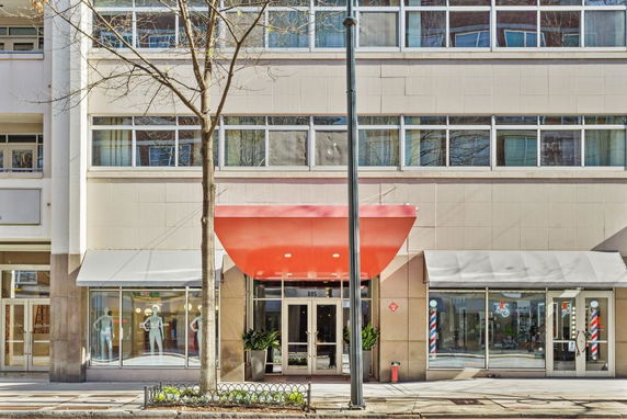 Front view of a multi-story building with large windows and a red awning above the entrance.