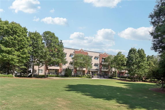 Front view of a multi-story building with a lawn and surrounding trees.