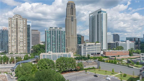 A view of a cityscape with multiple high-rise buildings and a parking area in the foreground.