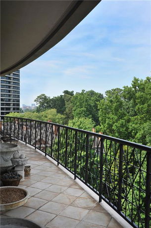 Curved balcony view with railing and lush greenery in the background.