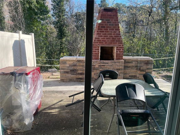 Outdoor brick fireplace and patio area with chairs and a table.