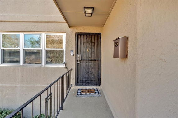 Front entrance view of a house with a metal door and adjacent windows.