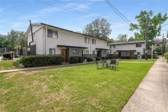 Front view of two-story residential buildings with a lawn and outdoor seating.
