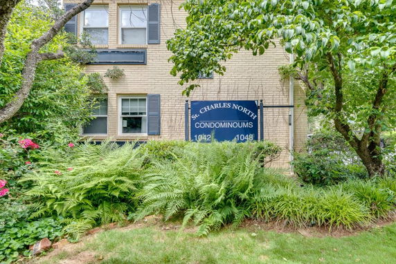 Front view of a condominium building with windows and a sign.