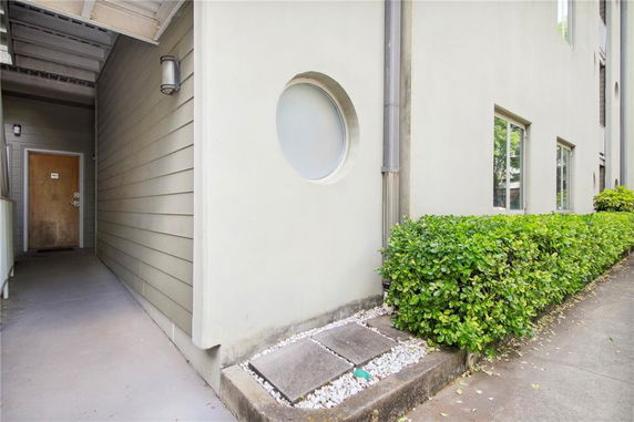 Partial view of a building with a circular window and a pathway leading to a wooden door.