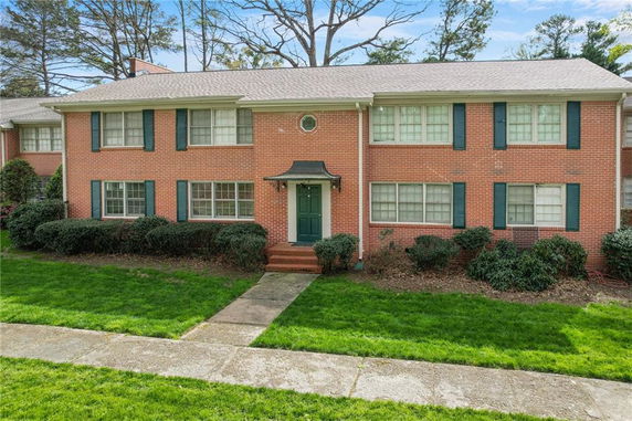 Front view of a two-story brick house with green shutters.