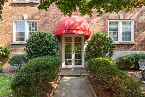Front entrance of a brick building with a red awning and glass door.