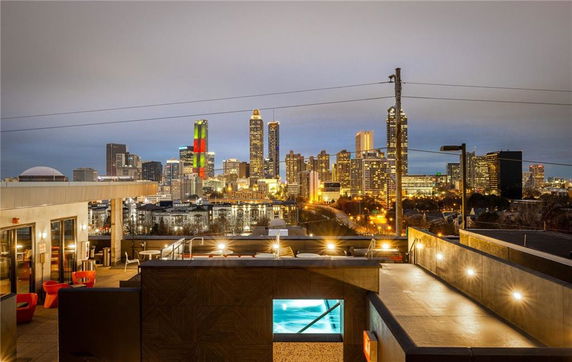 Rooftop with seating area and view of city skyline at night.