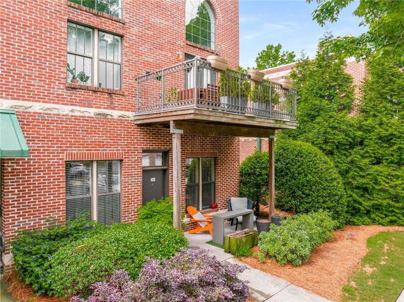 Front view of a brick building with a small balcony and patio area.