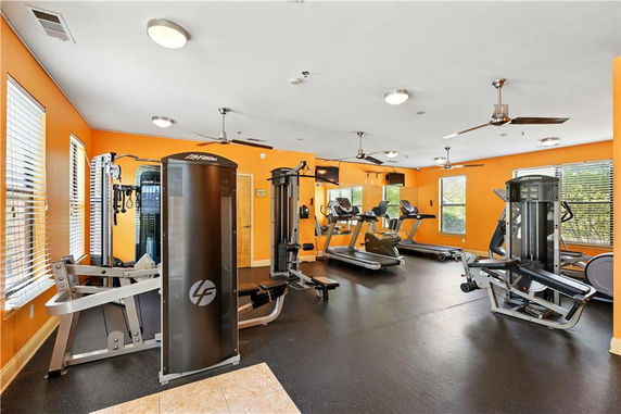 Gym area with exercise machines and equipment in a brightly colored room.