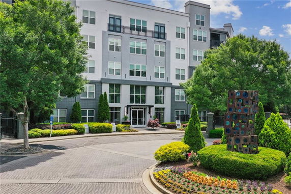 Front view of a multi-story apartment building with a modern exterior and landscaped entrance.