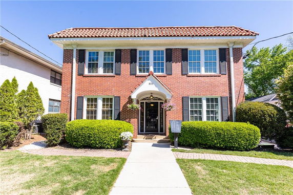 Front view of a two-story brick house with a tiled roof and multiple windows.