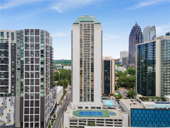 Front view of a high-rise building with tennis court on the rooftop.