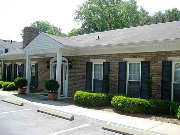 Front view of a single-story brick building with a columned entrance and a chimney.
