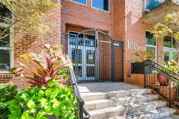 Front view of a brick building with gated entrance and stairs.