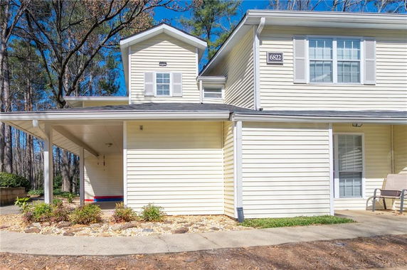 Front view of a two-story house with a carport and beige siding.