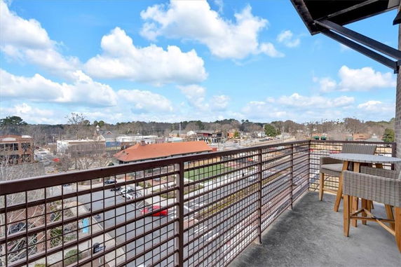View from a balcony overlooking a neighborhood with buildings and trees in the distance.