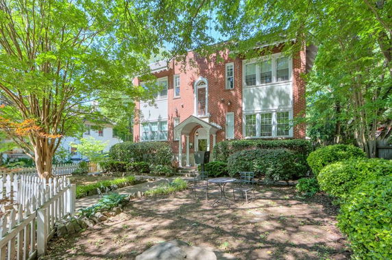 Front view of a two-story brick house with a small porch and arched entryway.