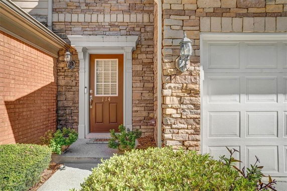 Front entrance of a house with stone and brick exterior walls and a single garage door.