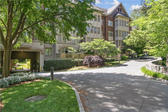 Front view of a multi-story building with a driveway and surrounding trees.