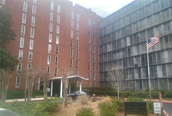 Front view of a multi-story brick building with large windows and an entrance canopy.