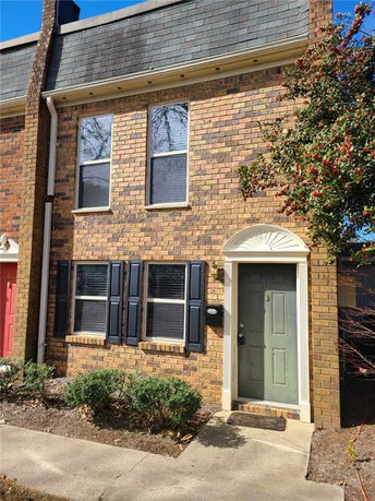 Front view of a two-story brick townhouse with a grey door and blue shutters.