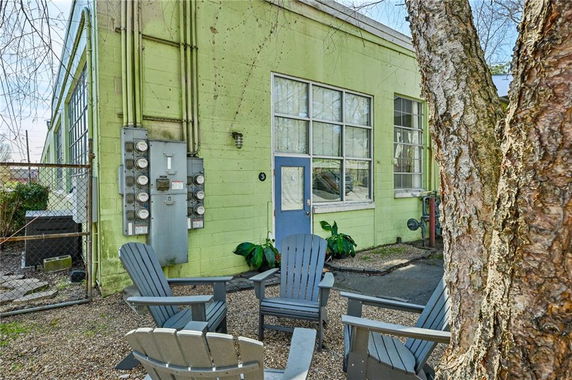Front view of a single-story, green-painted building with large windows and a utility area.