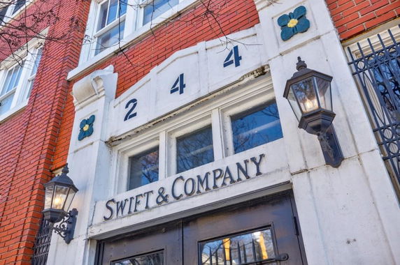 Front view of a brick building with decorative lamps and signage 'Swift & Company'.