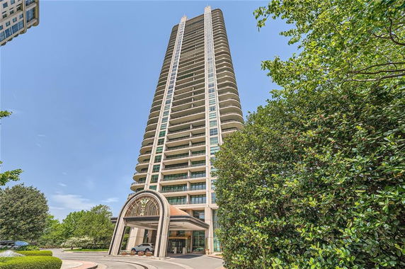 Front view of a tall residential building with multiple balconies.