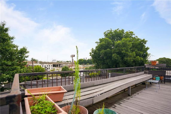 Rooftop area with benches, potted plants, and a view of trees and buildings.