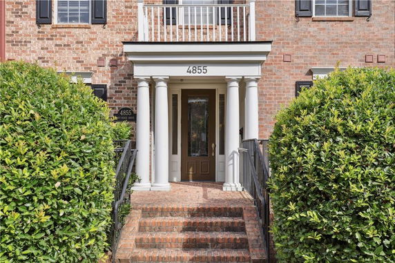 Front view of a brick house entrance with columns and steps.