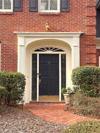 Front view of a house entrance with a black door and brick exterior.