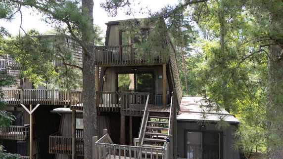Front view of a multi-story wooden house with balconies and stairs.