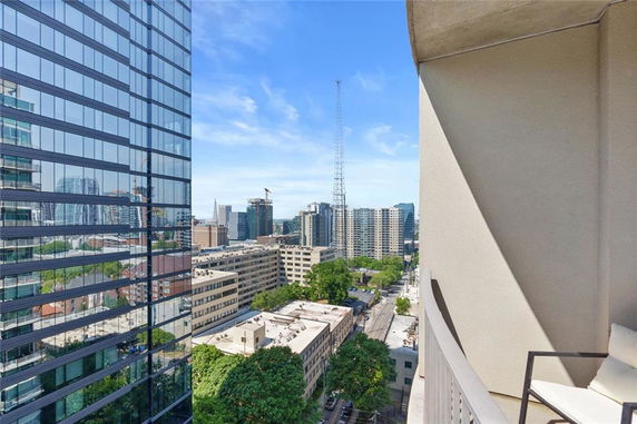 Panoramic view of cityscape with modern buildings and a balcony in the foreground.