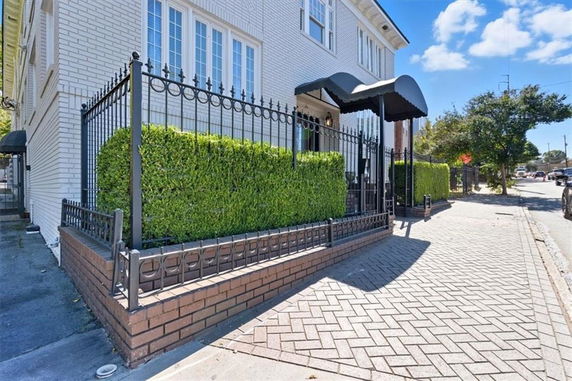 Front view of a building with white brick exterior and black wrought iron fence.
